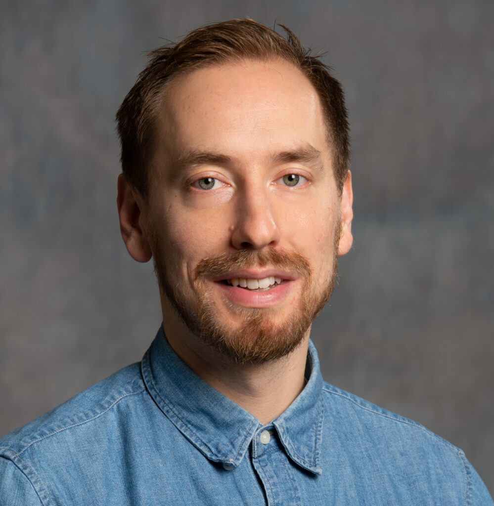 Portrait of a man with light brown hair and a blue button up shirt