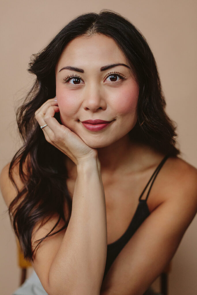 Glam studio portrait of a person with long wavy black hair and black tank top.