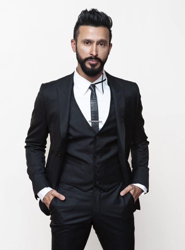 Portrait of man in a suit with a boxed beard and quiffed dark hair.