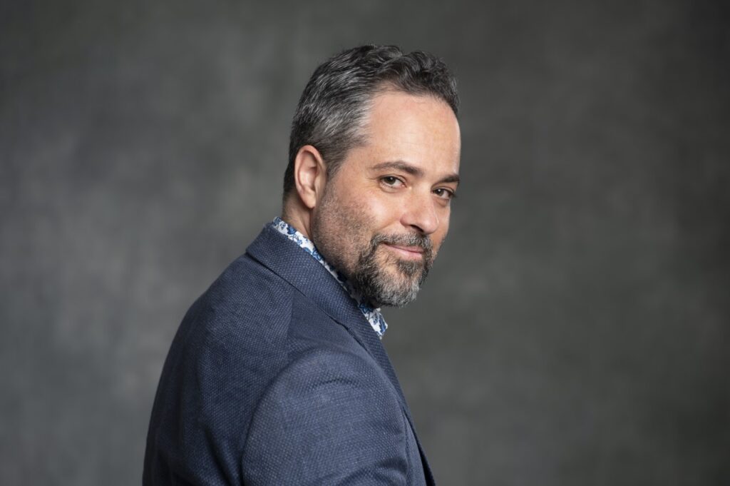 Studio portrait of a man looking back wearing a blue suit with gray beard