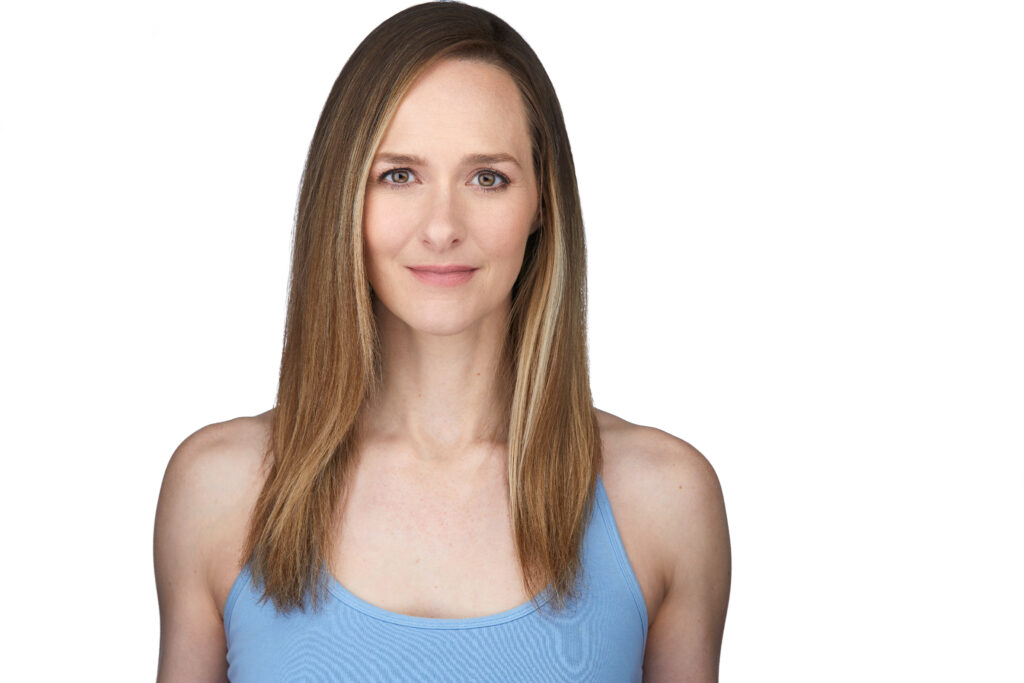 Portrait of a person with medium-length straight blonde hair wearing a baby blue tank top in front of a white background.